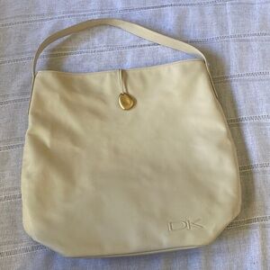 Donna Karen cream bohemian cosmetic bag with gold stone embellishment.